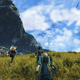 Xenoblade 3's main cast runs through a field with a large mountain and clouds in the background.